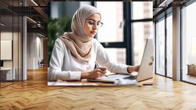 Portrait of successful Muslim businesswoman inside office with laptop, woman in hijab smiling and looking at camera, muslim office worker wearing glasses. Wall mural