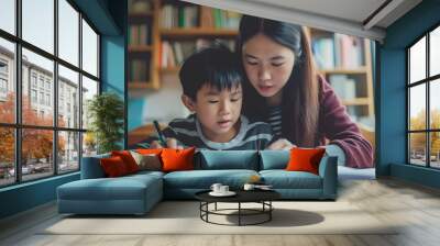 Asian mother doing homework with her son. Japanese mum helping kid to learn and study for school. Family portrait.  Wall mural