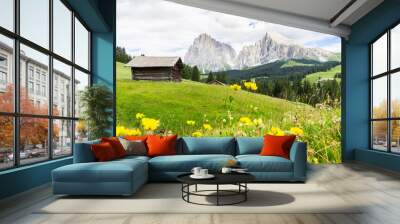 Alpe di Siusi or Seiser Alm, wooden huts and yellow flowers. Dolomites Alps in the back, South tyrol, Italy.  Wall mural