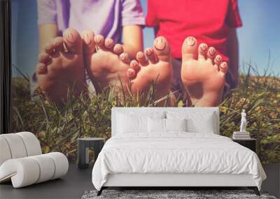 two children with smiley faces on their toes sitting in grass toned with a retro vintage filter Wall mural