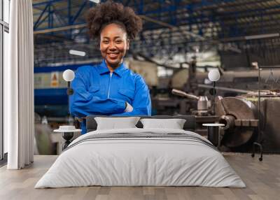 African American Young woman worker  in protective uniform operating machine at factory Industrial.People working in industry.Portrait of Female  Engineer looking camera  at work place. Wall mural