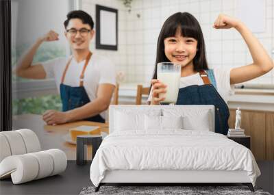 Asian  family enjoying breakfast at cozy kitchen, little girl daughter sitting on table, drinking milk with smiling father and mother in morning. Happy family in kitchen. Wall mural