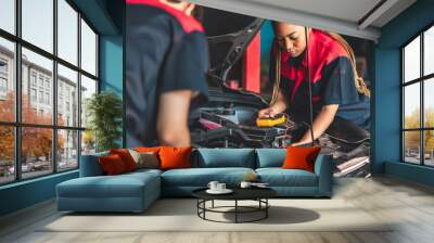 Auto service, repair, maintenance concept. Mechanic checks the car at the service station.African american woman  and asian engineer use tablet check car battery . Wall mural