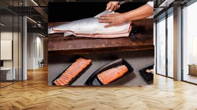 Chef's hand holding fresh piece of salmon.Closeup of chef hands preparing japanese food. Japanese chef making sushi at restaurant.Chef making traditional japanese sushi on wood board. Wall mural