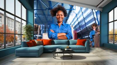 Engineer african woman wearing safety helmet working and checking machine  automotive part warehouse factory.Happy female  worker looking at the camera. Wall mural