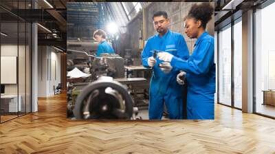 Engineer senior asian man and african woman wearing safety helmet working and checking machine  automotive part warehouse. Factory for the manufacture and processing. Wall mural