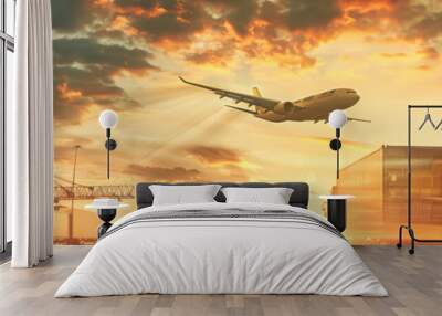 A cargo plane flies over a busy port at sunset, with large shipping containers lined up in the foreground Wall mural