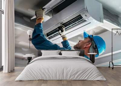 A man is seen diligently working on a ceiling air conditioner, conducting installation or repairs Wall mural