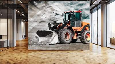 Bulldozer or loader moves the earth at the construction site against the blue sky. An earthmoving machine is leveling the site. Construction heavy equipment for earthworks. Wall mural