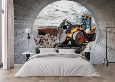 Bulldozer or loader moves the earth at the construction site against the sunset sky. Contrasting image of a modern loader or bulldozer. Construction heavy equipment for earthworks. Wall mural