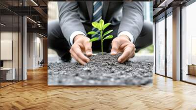 Businessman kneeling in the city, planting a young tree to promote environmental protection and green energy development Wall mural