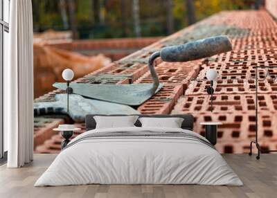 Construction trowel for laying bricks and blocks. Construction tool of a bricklayer. Hand working tool on the background of brickwork. Wall mural