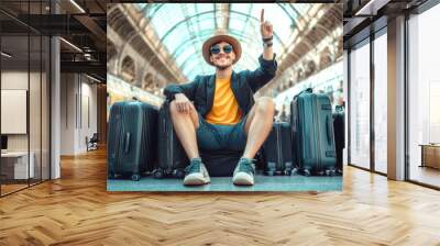 Happy young man celebrates travel at the train station with luggage, expressing excitement and adventure during his journey Wall mural