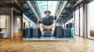 Happy young man with luggage celebrates at a bustling train station, reveling in his travel adventure surrounded by suitcases Wall mural