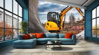 Mini excavator at the construction site on the edge of a pit against a cloudy blue sky. Compact construction equipment for earthworks. An indispensable assistant for earthworks. Wall mural