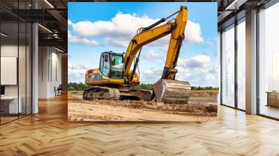 Powerful excavator at a construction site against a blue cloudy sky. Earthmoving equipment for construction. Development and movement of soil. Wall mural