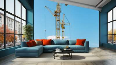 The work of tower cranes against the background of the sunset sky. Modern housing construction. Industrial engineering. Construction of mortgage housing. Wall mural