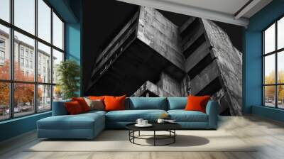 Low angle shot of a brutalist style concrete building with weathered surfaces, set against a dark sky Wall mural