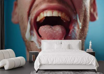 Close-up of a man's open mouth showing teeth and tongue against a blue background. Wall mural