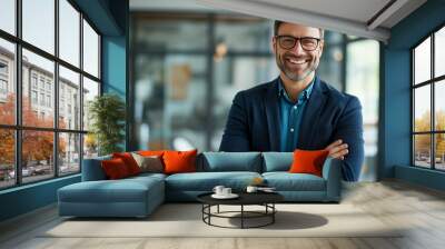 Confident young man smiling with arms crossed in a casual office setting. Wall mural