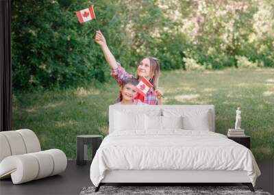 Family mom with son celebrating national Canada Day on 1st of July. Caucasian mother with child boy waving Canadian flags. Proud citizens celebrate Canada Day in park outdoors. Wall mural