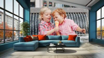 Group portrait of two white Caucasian cute adorable funny children toddlers sitting together sharing ice-cream food. Love friendship concept. Best friends forever. Wall mural