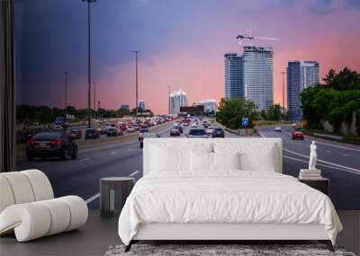 Night traffic. Cars on highway road at sunset evening in typical busy american city. Beautiful amazing night urban view with red, yellow and blue sky clouds. Sundown in downtown. Wall mural