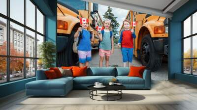 Proud happy children students boys and girl holding waving Canadian flags. Education and back to school in September. Group of friends kids near yellow school bus outdoor on school yard. Wall mural