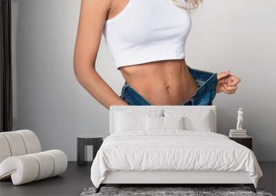 Diet concept and weight loss. Slim beautiful young blonde woman in oversize jeans on white background isolated Wall mural