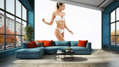 Woman with measure tape. Beauty perfect slim body: fit sporty and healthy woman posing at white background in underwear. Sport, wellness, fitness, diet, weight loss and healthcare concept Wall mural