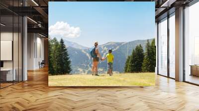 A woman and a boy are walking in summer mountains Wall mural