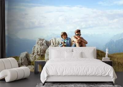 Two boys sitting on a rock in the mountains Wall mural