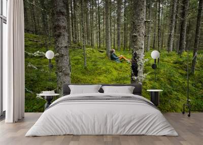 Woman sits in mossy green forest with sketch pad  Wall mural