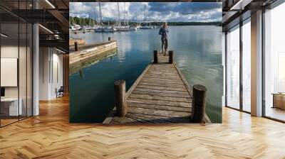 Woman stands on edge of dock in seaside harbor Wall mural