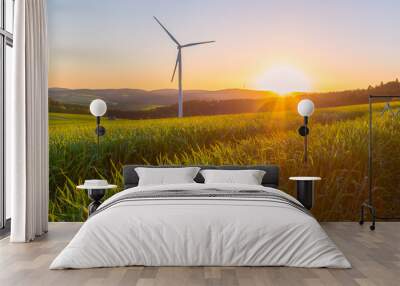 green field with wind turbine in the background at sunset Wall mural