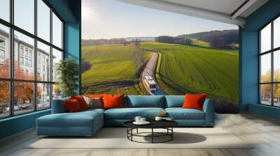 high angle view of bus driving on the winding road through the fields in the countryside under the blue sky Wall mural