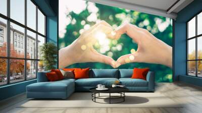 Woman hand do heart shape on green nature tropical background. Wall mural