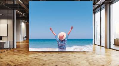 Young woman rise hand up to sky feel relax and free with summer beach background. Wall mural