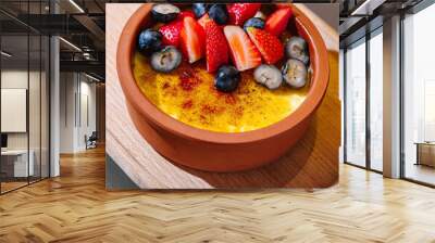 Delicious creme brulee dessert with fresh blueberries and strawberries on top Wall mural