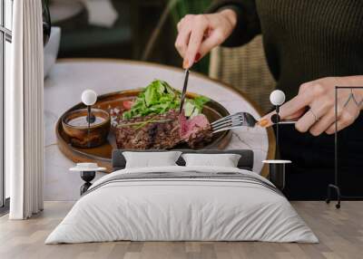 female hands in a restaurant at the table cut beef striploin steak Wall mural