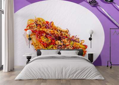 Wok noodles with chicken and vegetables on white plate over purple background Wall mural