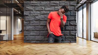 African man model laughing in red t-shirt against brick wall with facepalm Wall mural