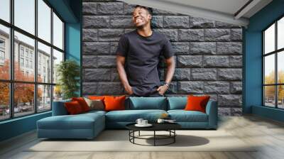 Handsome african american man in black t-shirt laughing against brick wall Wall mural