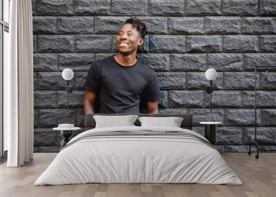 Handsome african american man in blank black t-shirt standing against brick wall Wall mural