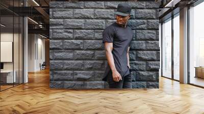 Handsome african american man in blank black t-shirt standing against brick wall Wall mural