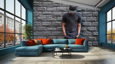 Handsome african american man in blank black t-shirt standing against brick wall Wall mural