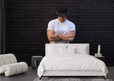 man in white t-shirt standing against brick wall with arms crossed Wall mural