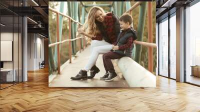 mother with son sitting on a bridge in sunny day Wall mural