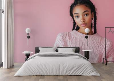 Black woman wearing a pink sweater and posing in studio Wall mural