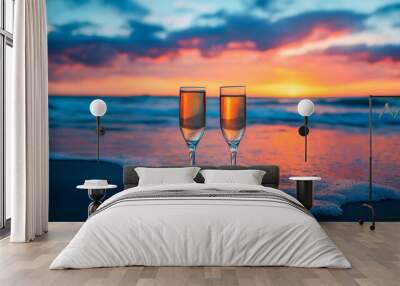 Two glasses of champagne on beautiful beach with blue and orange sky on background Wall mural